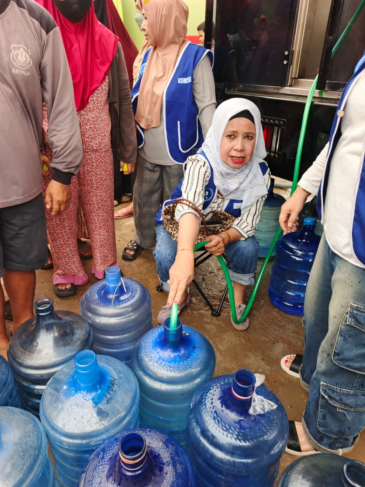 Ibu Erni Sutrisni salah seorang pengurus IWAPI Ketapang sedang menuangkan air ke galon warga Desa Kalinilam pada kegiatan penyaluran air siap minum kolaborasi KADIN,IWAPI,HIPMI dan TNI di desa Kalinilam pada hari Sabtu (26/9/2025) /dok:Ys/Iwapi